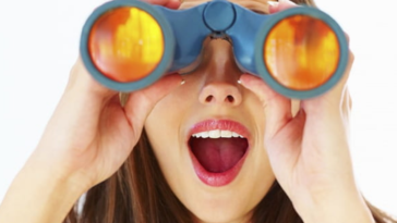 young girl looking-through-binoculars-at-the-beach