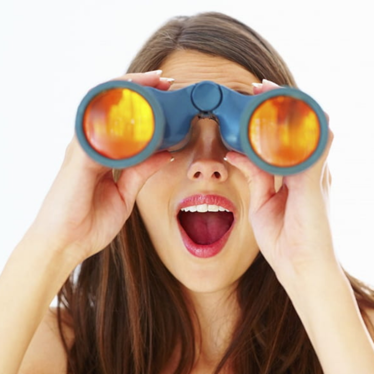 young girl looking-through-binoculars-at-the-beach